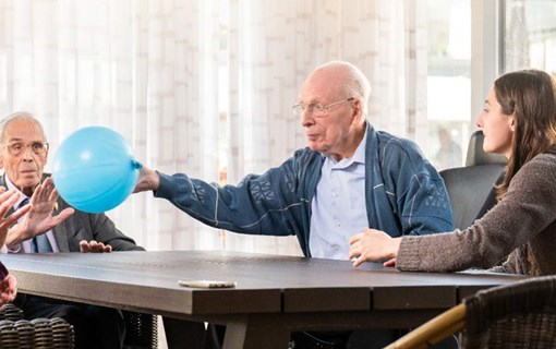 Ouderen spelen met een balon aan tafel